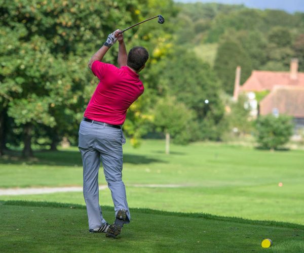 Man striking golf ball in red shirt